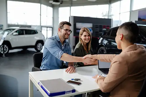 Customers shaking hands with a dealer in the showroom