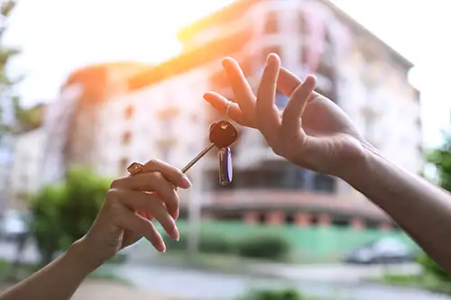 Blurred out of focus building in the background with a set of keys changing hands in focus