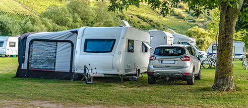 A caravan with tent and car in a green field