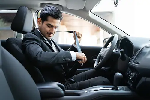 Business man in a suit putting his seat belt on in a car
