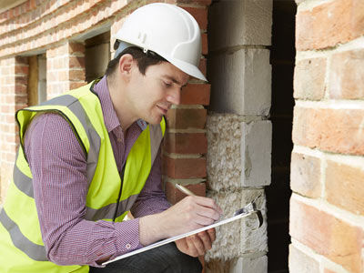 A Building Inspector has a look underneath a house